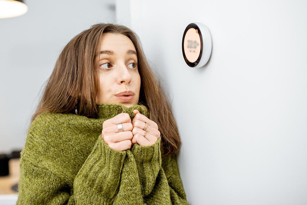 Cold woman checks thermostat